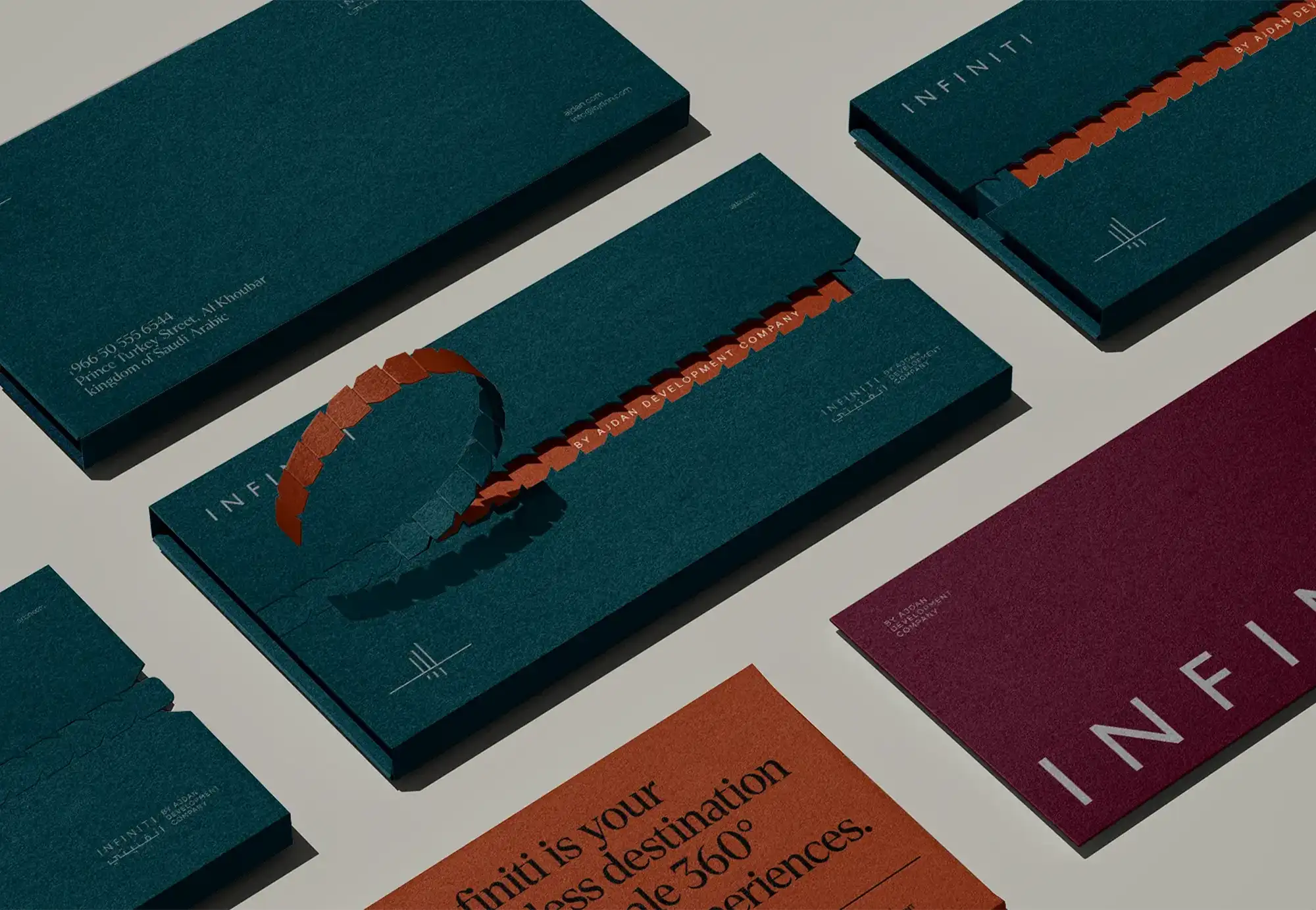 Dark green Infiniti brand stationery laid out on a gray surface
